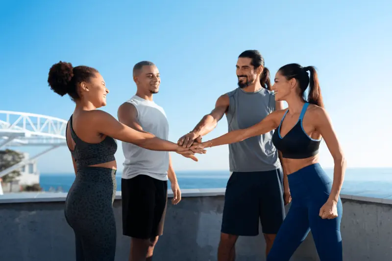 Four colleagues joining hands after a workout